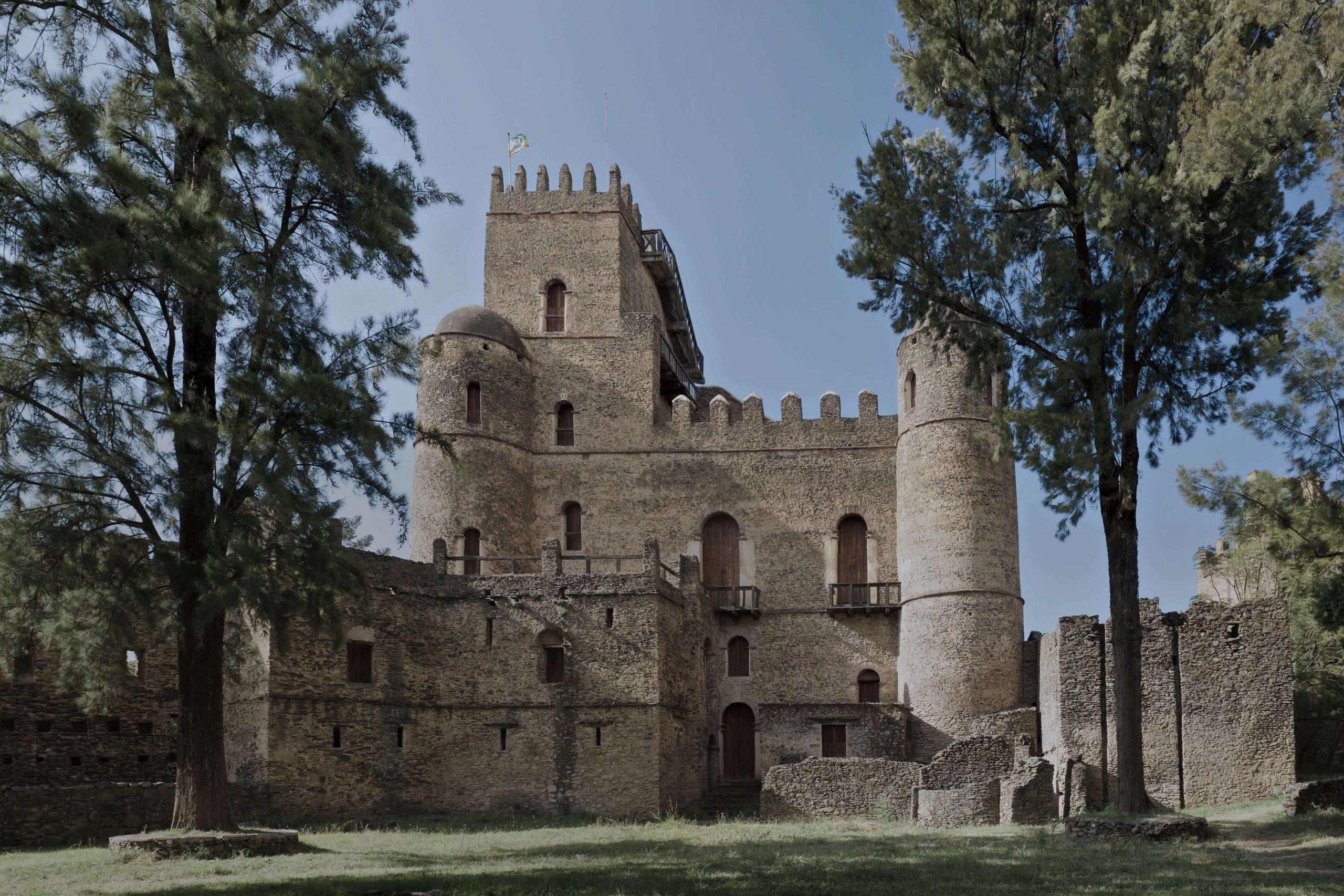 Fasilides castle in the Royal Enclosure at Gondar, a stone tower with crenellations and a domed turret, framed by tall trees
