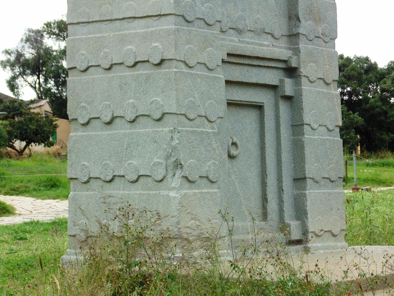 The base of a granite stele at Aksum carved with a false door complete with a stone door-ring, and rows of carved beam ends above it imitating the storeys of a building