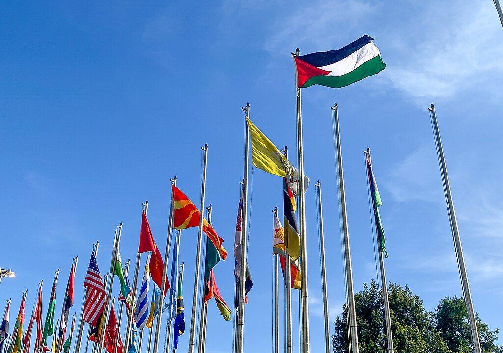 A long row of national flags on tall poles against a blue sky at the United Nations Conference Centre in Addis Ababa